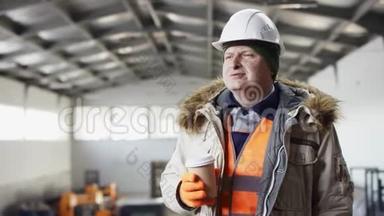 戴着安全帽、穿着工作服的人正站在机库的中间，在机库里喝杯咖啡休息一下